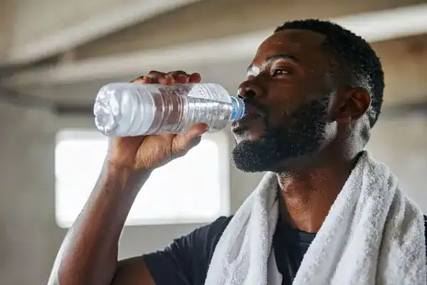 Image of man drinking water to improve hydration Bexhill after work out.
